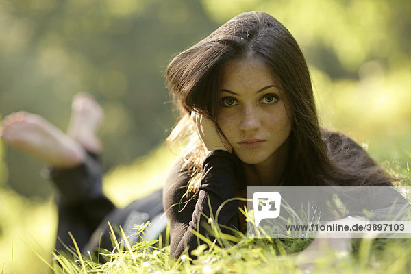 Junge Frau liegt im Gras