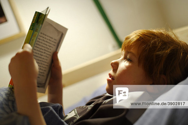 Kind Junge beim Lesen im Bett