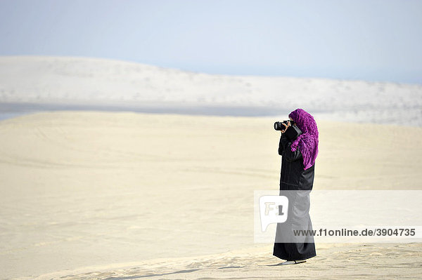 Fotografin  Araberin in traditioneller Tracht mit abayah und Schleier  Strand Khor Al Udeid Beach  auch Khor El Deid  Inland Sea  Wüstenwunder von Katar  Emirat Qatar  Persischer Golf  Naher Osten  Asien