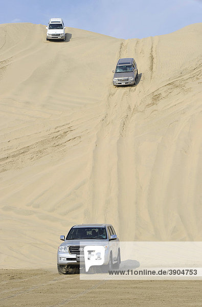 Drei Off-Roader während Fahrt auf Sanddüne  Emirat Katar  Qatar  Persischer Golf  Naher Osten  Asien