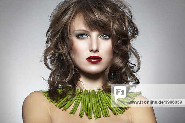 Portrait einer jungen Frau mit grünen Bohnen als Halskette  Schmuck