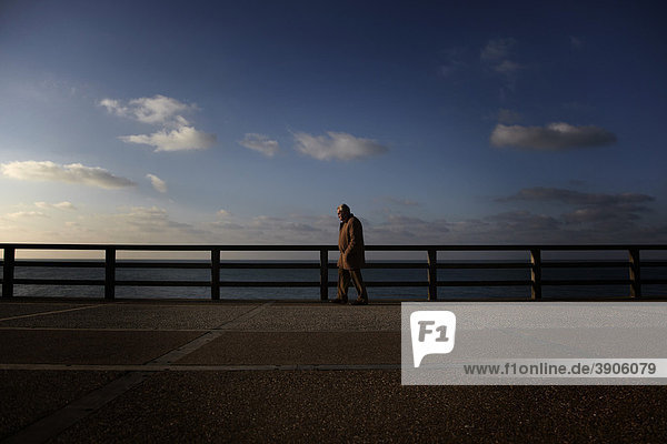 An elderly man is walking on a beach promenade  La CÙte d'alb‚tre coast  Normandy  France  Europe