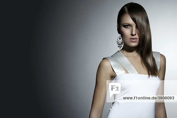 Portrait einer jungen Frau im weißen Kleid  Ohrring  direkter Blick  Fashion