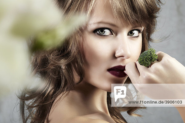 Portrait einer jungen Frau  hält ihre Hand mit einem Ring aus Brokkoli verführerisch an ihren Mund  Schmuck