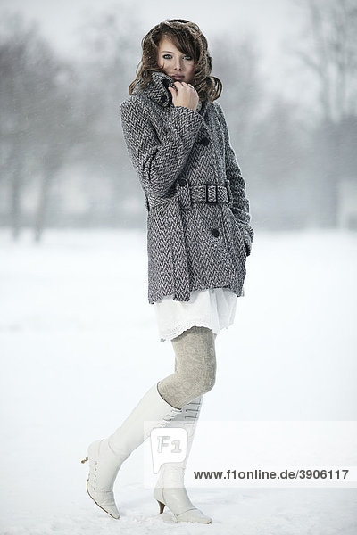 Junge Frau im Schnee  ihre Hand den Mantelkragen haltend