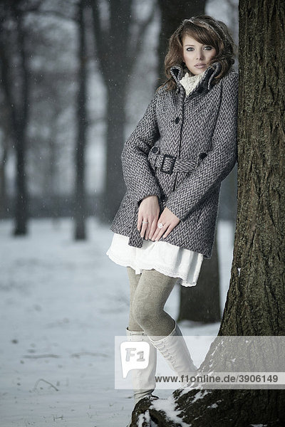 Young woman leaning against a tree trunk