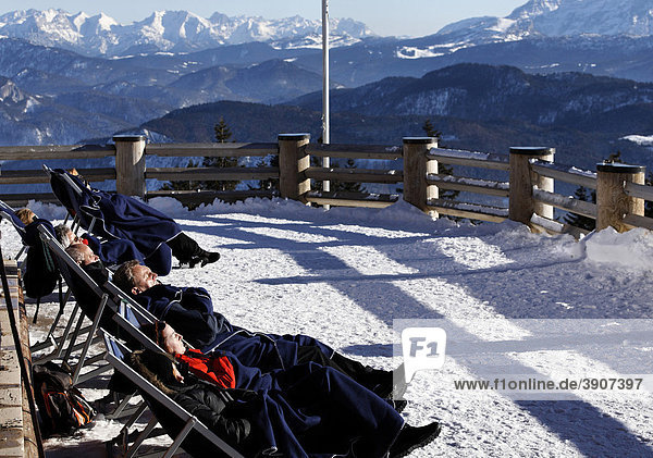 Menschen genießen die Wintersonne auf der Terrasse eines Bergrestaurants auf der Kampenwand  Chiemgau  Oberbayern  Deutschland  Europa