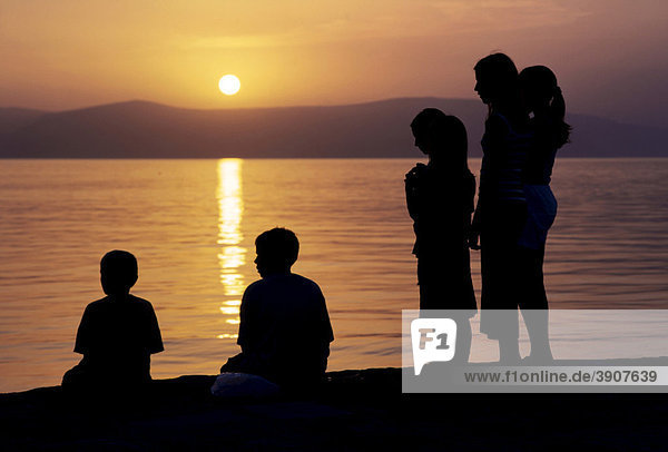 Silhouetten von Menschen im Sonnenuntergang an der Küste  Kroatien  Europa