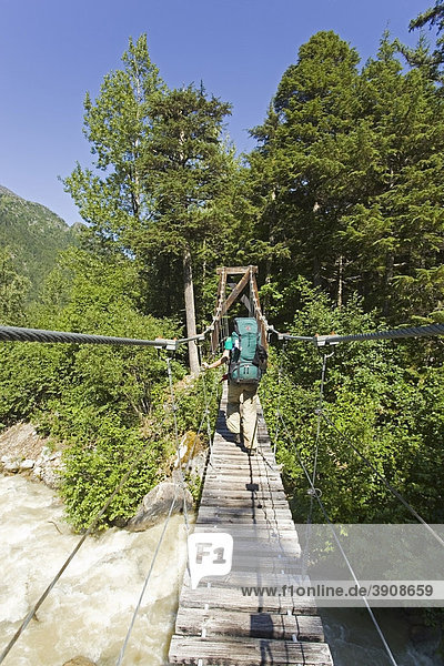 Taja River  suspension bridge  young woman hiking  backpacking  hiker  Pacific Northwest Coastal Rain Forest  historic Chilkoot Trail  Pass  Alaska  USA