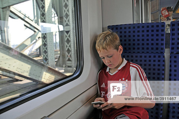 Achtjähriger Junge sitzt alleine in einem Regionalzug und spielt  Deutschland  Europa