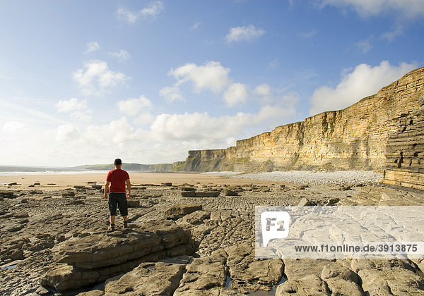 Man standing on a stone and looking at the beach and the cliffs  coast  Nash Point  Glamorgan Heritage Coast  South Wales  Wales  United Kingdom  Europe