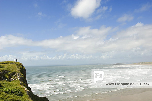 Two people on a cliff looking at the beach and the waves  Rhossili Beach  Gower Peninsula  Wales  United Kingdom  Europe