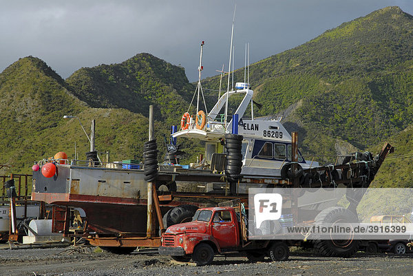 Ein alter LKW und ein Boot vor den grünen Hügel in Ngawi an der südlichen Küste der Nordinsel  Neuseeland