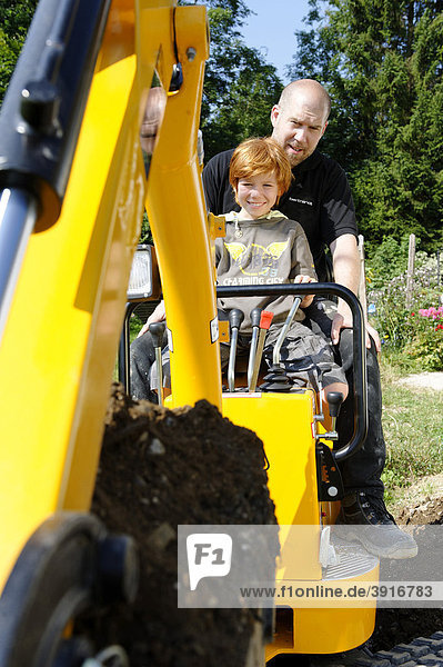 Child with his father on a mini digger