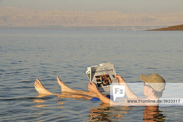 Tourist liest Zeitung im Toten Meer  hoher Salzgehalt  bei Suwaymah  Jordanien  Naher Osten  Orient
