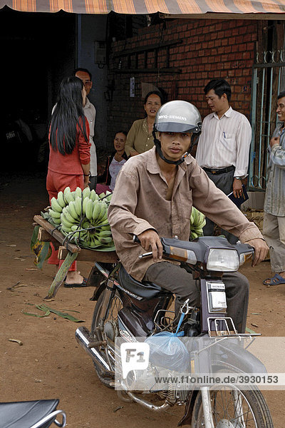 Mr. Thu bringt seine Bananenernte mit dem Moped zu Nhon  Frucht- und Gemüsehandel in Buon Ma Thuot City in Vietnam  Südostasien