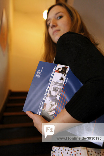 Trainee in the new profession of new media design conception and visualisation holding a textbook for professional training in the media industry fundamentals of print and digital media