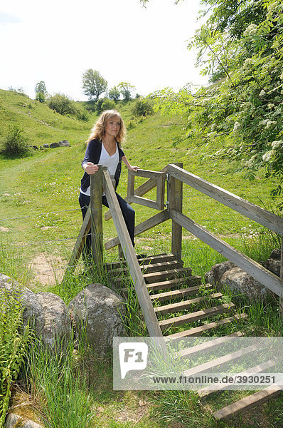 Junge Frau an einem Tor in einem Naturpark