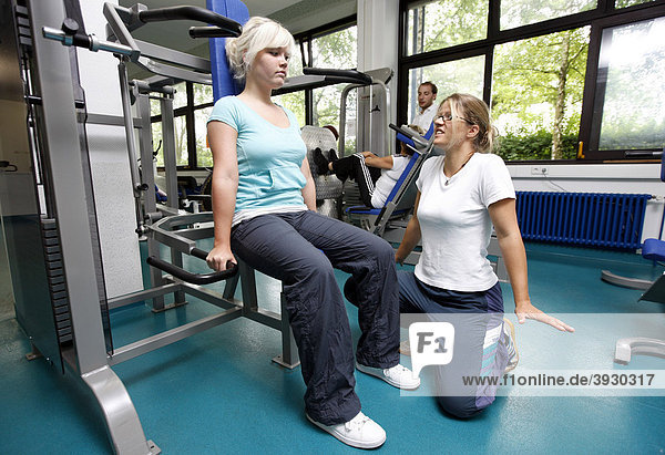 Patientin beim Muskelaufbautraining an verschiedenen Kraftmaschinen im Trainingsraum  Physiotherapie in einem neurologischen Rehabilitationszentrum  Bonn  Nordrhein-Westfalen  Deutschland  Europa