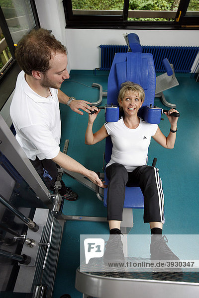 Patientin beim Muskelaufbau Training an einer Kraftmaschine im Trainingsraum  Physiotherapie in einem neurologischen Rehabilitationszentrum  Bonn  Nordrhein-Westfalen  Deutschland  Europa