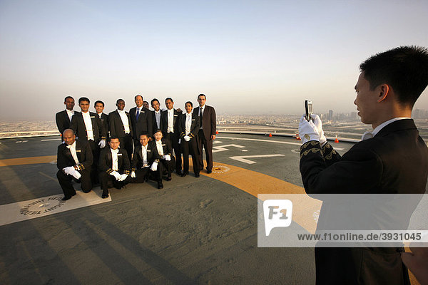 Butler sind auf der Hubschrauberlandeplattform auf dem Dach des Luxushotel Burj Al Arab angetreten um einen VIP Gast zu empfangen  machen eine Erinnerungsfoto  Dubai  Vereinigte Arabische Emirate  Naher Osten