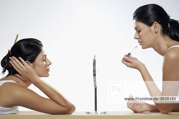Zwei junge Frauen beim Schminken sitzen sich gegenüber  Beauty