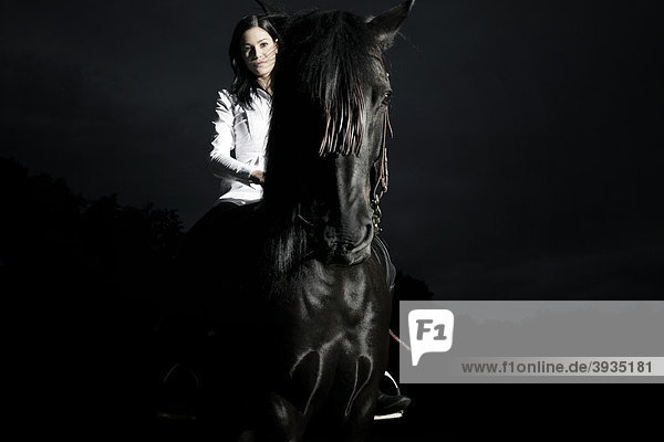 Junge Frau reitet auf ihrem dunkelbraunen Pferd