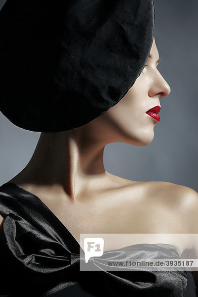 Seitliches Portrait einer jungen Frau im schwarzen Kleid und schwarzem Hut  Fashion