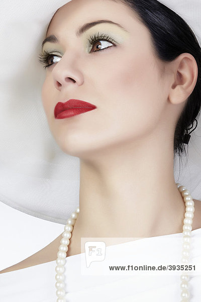Portrait einer jungen Frau mit weißem Sommerhut  weißem Kleid und Perlenkette