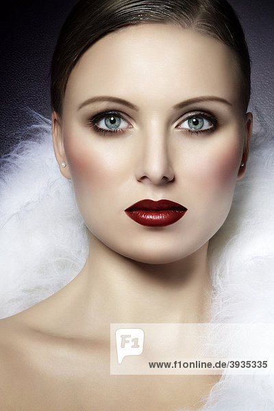 Portrait of a young woman  wrapped in a white fur  deep red lipstick  direct look  fashion  glamour mouth