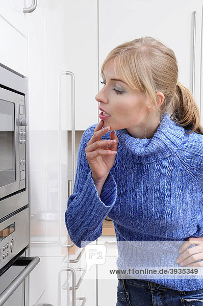 Frau kocht mit der Mikrowelle in einer modernen Küche