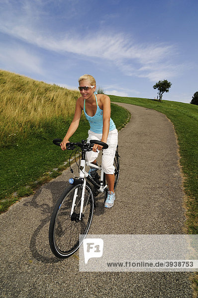 Young woman riding a bicycle  Olympic Park  Munich  Bavaria  Germany  Europe