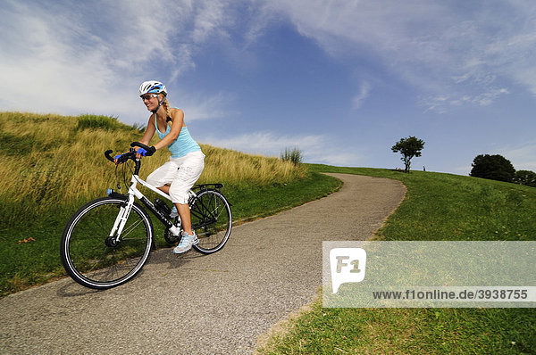 Young woman riding a bicycle  Olympic Park  Munich  Bavaria  Germany  Europe