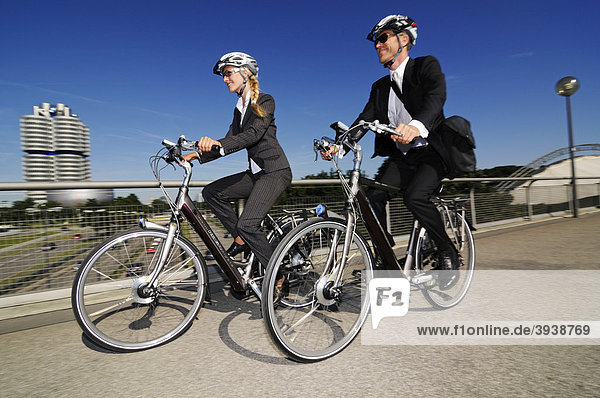 Business people riding on electric bicycles  pedelecs  Olympic Stadium  Munich  Bavaria  Germany  Europe