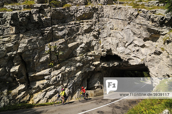 Cyclists in front of rock arch  L'Auberson  Canton Vaud  Switzerland  Europe