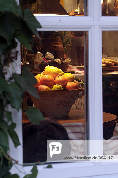 Blick von außen durch ein Fenster in eine vorweihnachtlich  mit Obstschale und Gebäck geschmückten Küche