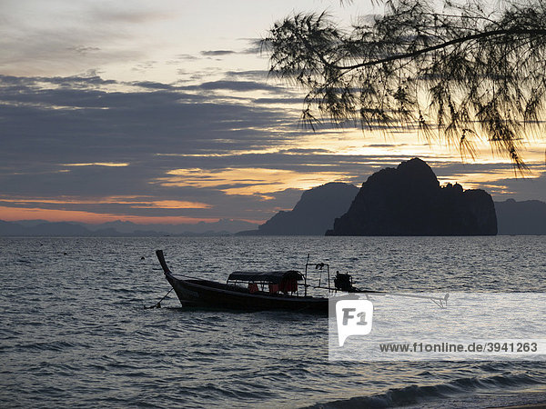 Longtailboot in der Morgendämmerung mit Blick auf eine Felsengruppe vor der Insel Ko Hai  Ko Ngai  Andamanensee  Provinz Satun  Südthailand  Thailand  Asien