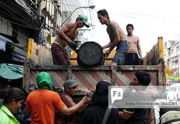 Men emptying mud bucket  Bangkok  Thailand  Asia