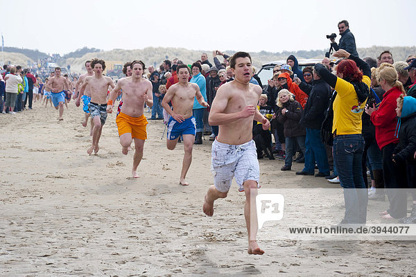 Tourists in bathing suits running the traditional Paasduik Easter diving event on the beach in the North Sea resort of Renesse  opening event of the holiday season  Duiveland Schouwen  Zeeland  Netherlands  Europe