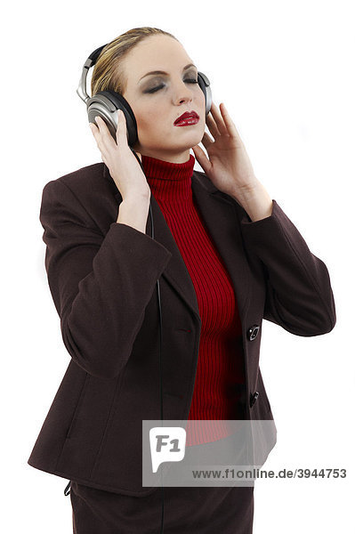 Junge Frau in Business-Outfit hört mit Kopfhörer