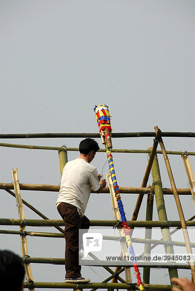 Mann legt bunt geschmückte Rakete aus Bambus auf Abschussrampe Pi Mai Laotisches Neujahrsfest Volksfest Phongsali Stadt Phongsali Provinz Phongsaly Laos Südostasien Asien