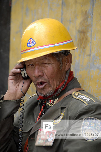 Construction worker  Chinese foreman wearing a helmet and uniform giving orders by radio  Lhasa  Himalayas  Tibet Autonomous Region  People's Republic of China  Asia