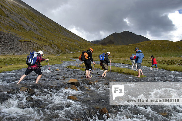 Trekking tourism  group of hikers wading barefoot through a clear mountain stream  Tsotup-chu valley  an old pilgrims' path through the high mountains of the Ganden Monastery to Samye  Himalayas  Tibet Autonomous Region  People's Republic of China  Asia