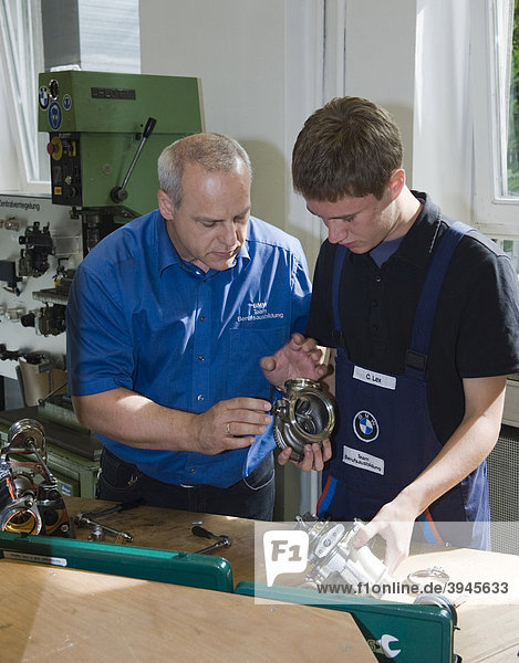 Master explaining to an apprentice while working on part of an engine in the BMW training center for automotive mechatronics  Munich  Bavaria  Germany  Europe