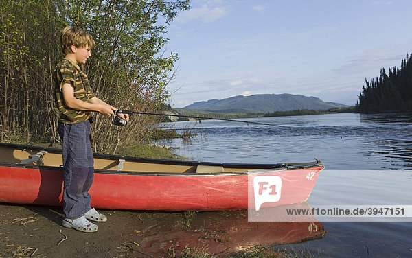 Kleiner Junge beim Angeln neben einem Kanu  Teslin River  Yukon Territory  Kanada