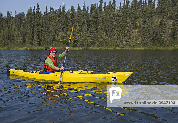 Young woman in kayak  paddling  kayaking  Caribou Lakes  upper Liard River  Yukon Territory  Canada