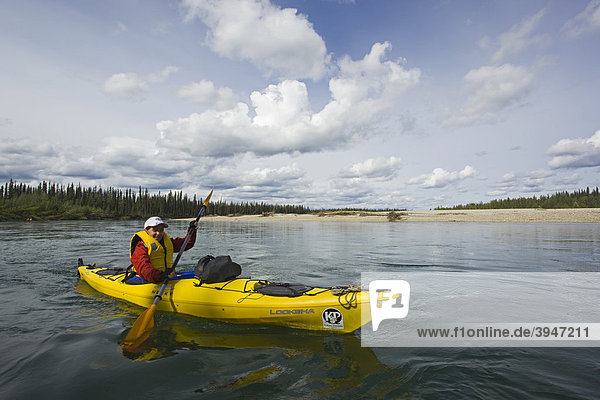 Young woman in kayak  paddling  kayaking  wide open landscape  upper Liard River  Yukon Territory  Canada