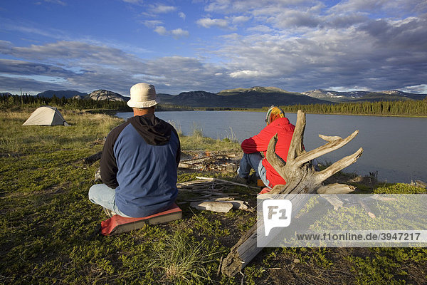 People sitting on a camp fire  evening  tent behind  camping  Yukon River  Yukon Territory  Canada