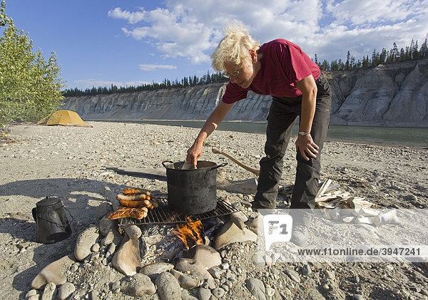 Frau kocht am Lagerfeuer  Grill-Würstchen  Bratwurst  Wasserkocher  Topf  oberer Liard River Fluss  Yukon Territory  Kanada