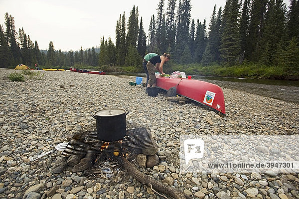 Kochen am Lagerfeuer  Topf  dahinter ein Kanu als Tisch  Schotterbank  oberer Liard River  Yukon Territory  Kanada